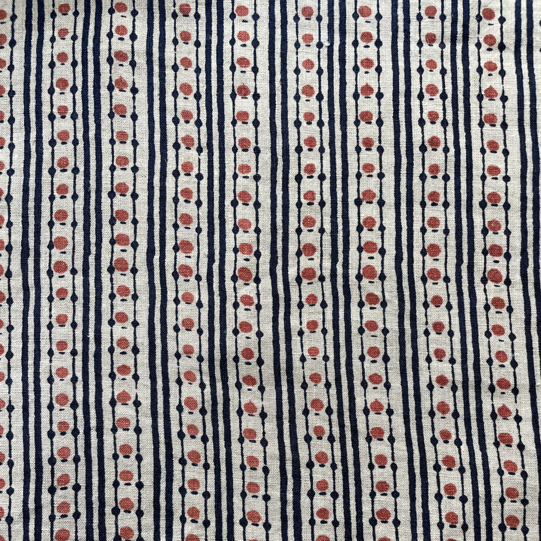 Block printed fabric in a dotted stripe in red and indigo on natural linen.