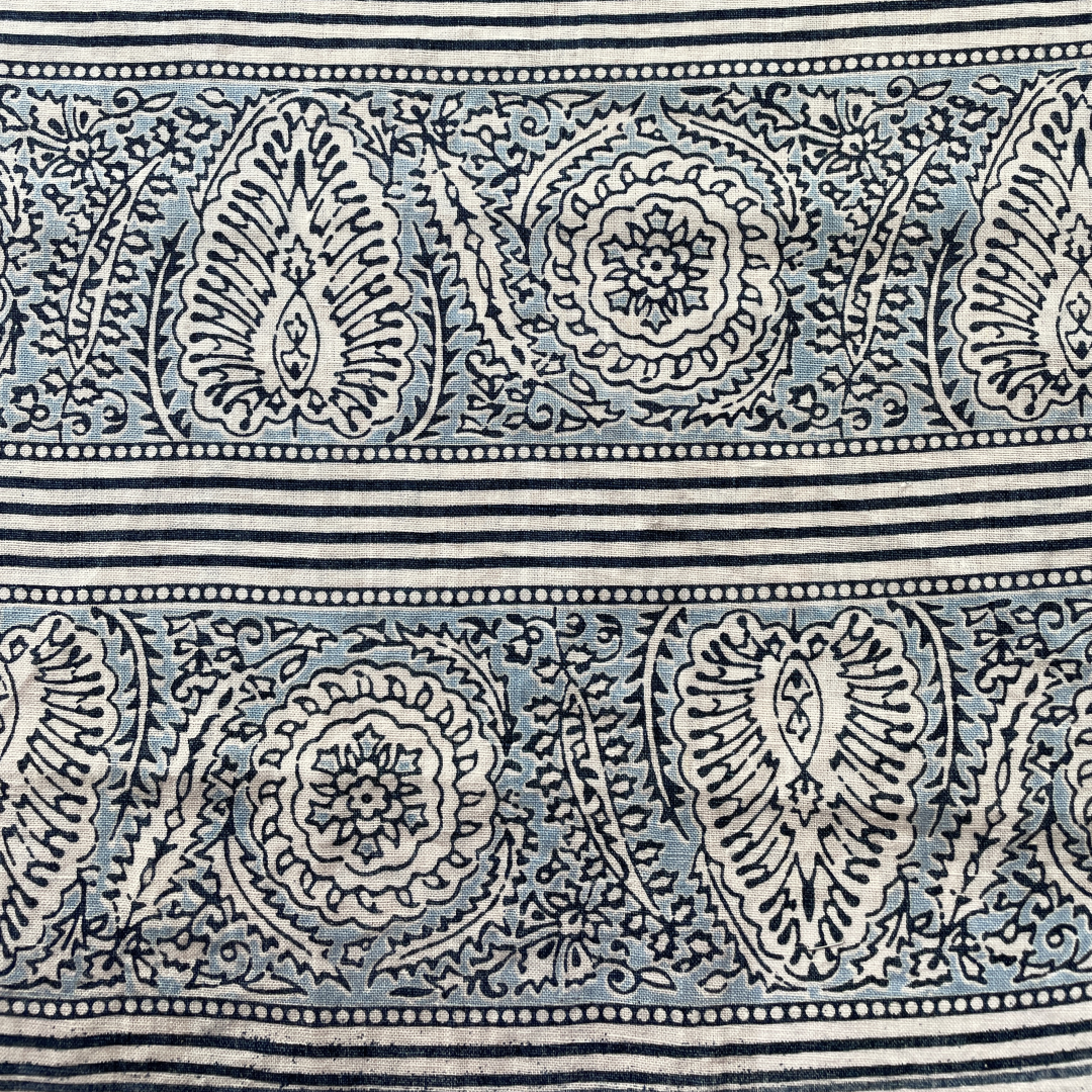 Block printed fabric in an ornamental paisley stripe in indigo and blue on linen.