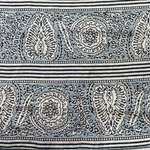 Block printed fabric in an ornamental paisley stripe in indigo and blue on linen.