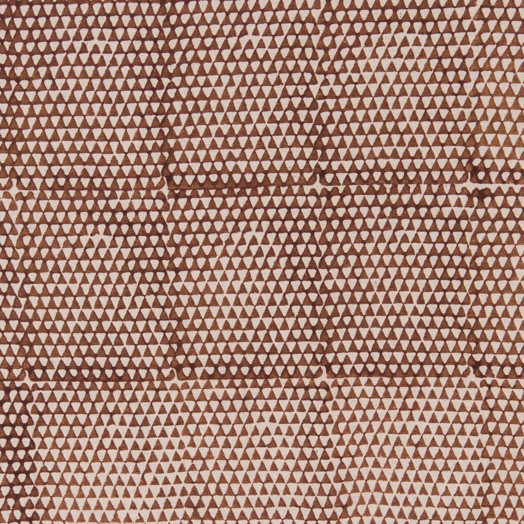 Detail of fabric in a small-scale triangle print in rust on a tan field.