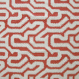Detail of fabric in a playful meandering print in white on a coral field.