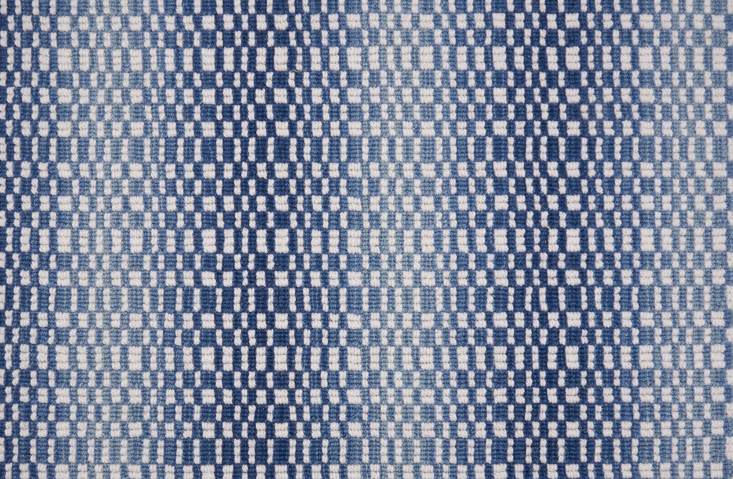 Broadloom carpet with a white checkerboard pattern with an ombré effect in shades of blue.