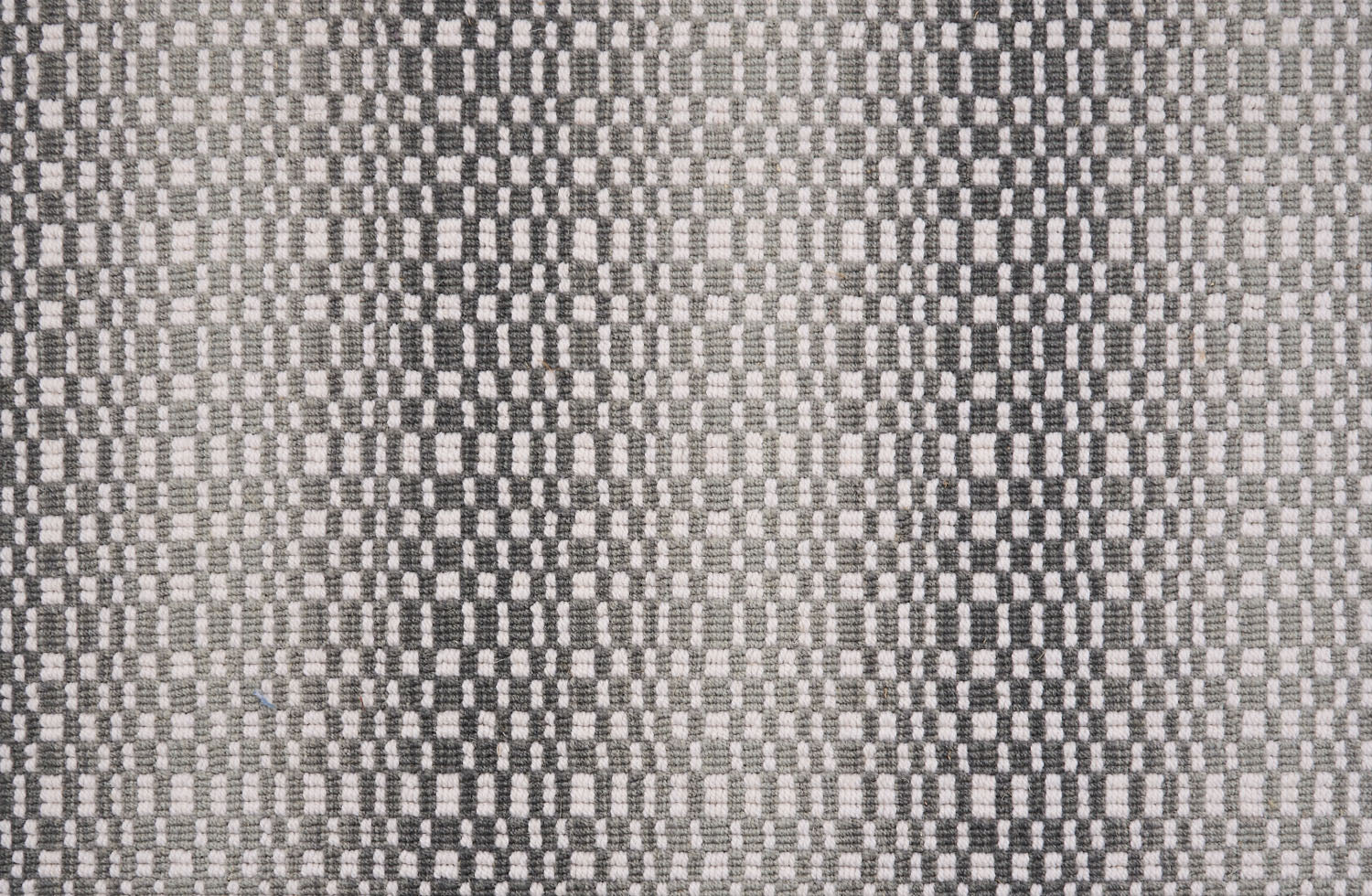Broadloom carpet with a white checkerboard pattern with an ombré effect in shades of grey. 