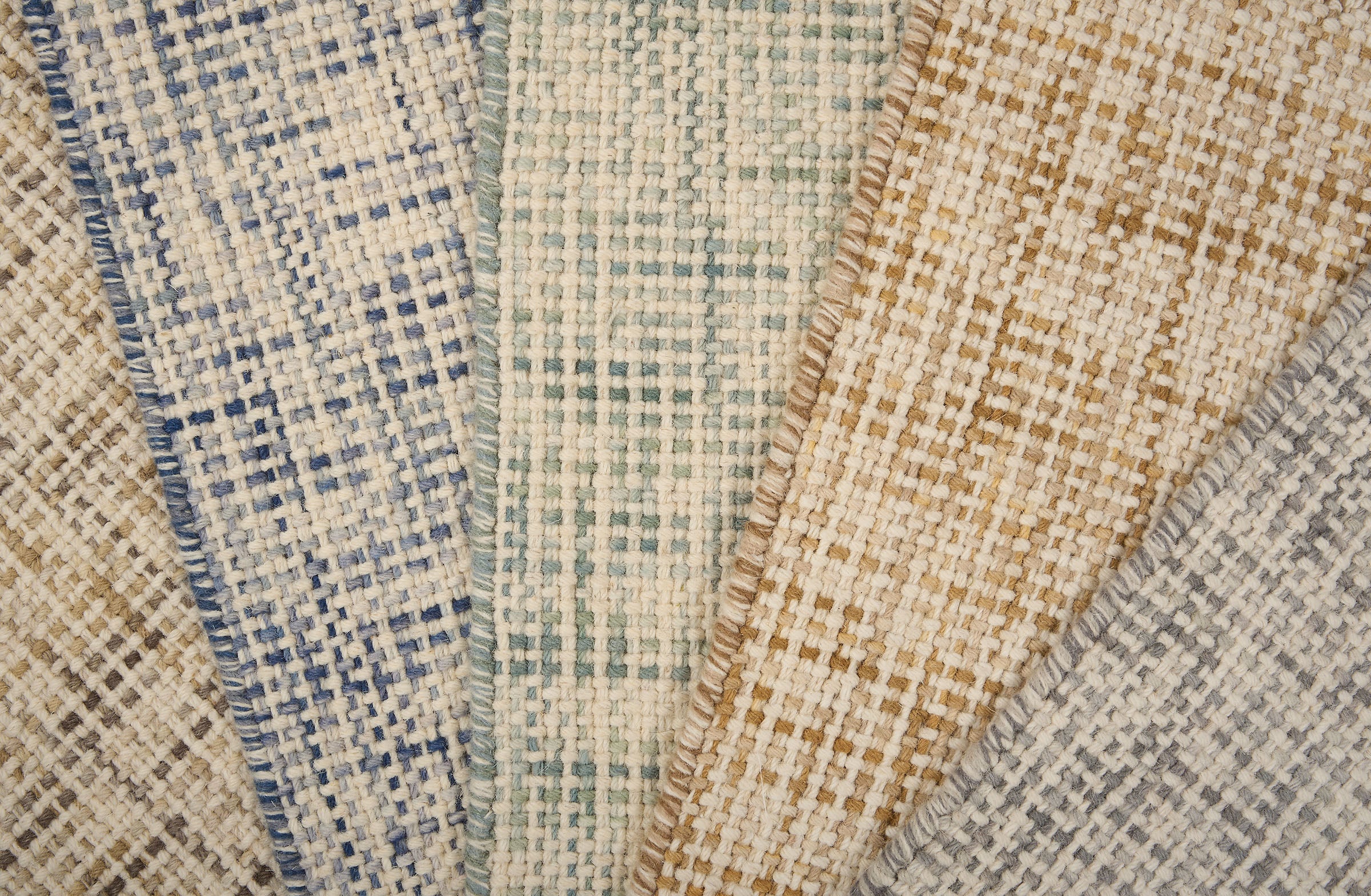 A pile of broadloom carpets in textural basket weaves in an array of colors. 