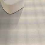 Textured gray carpet with a chair and red pillow in the corner