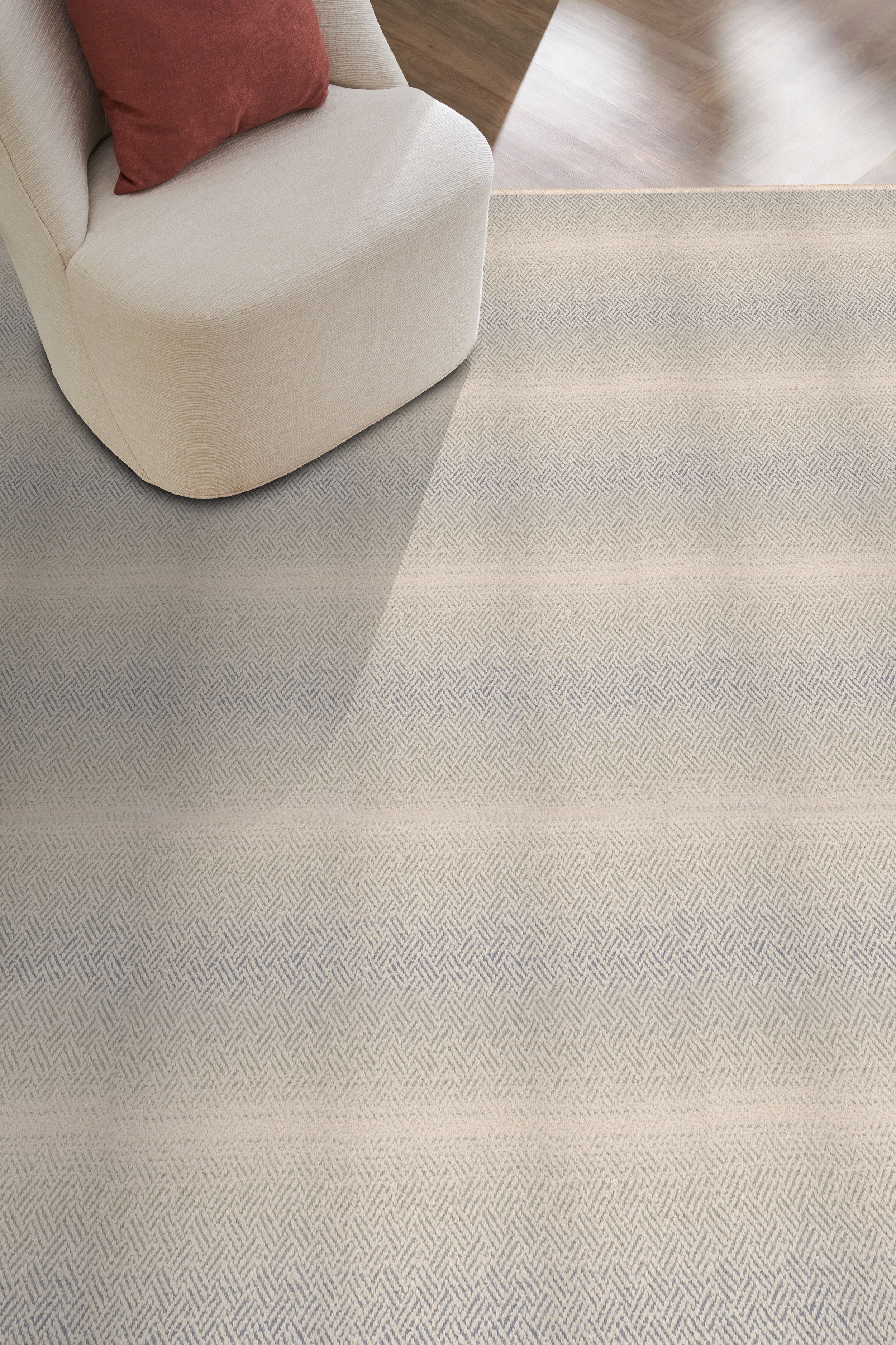 Textured gray carpet with a chair and red pillow in the corner