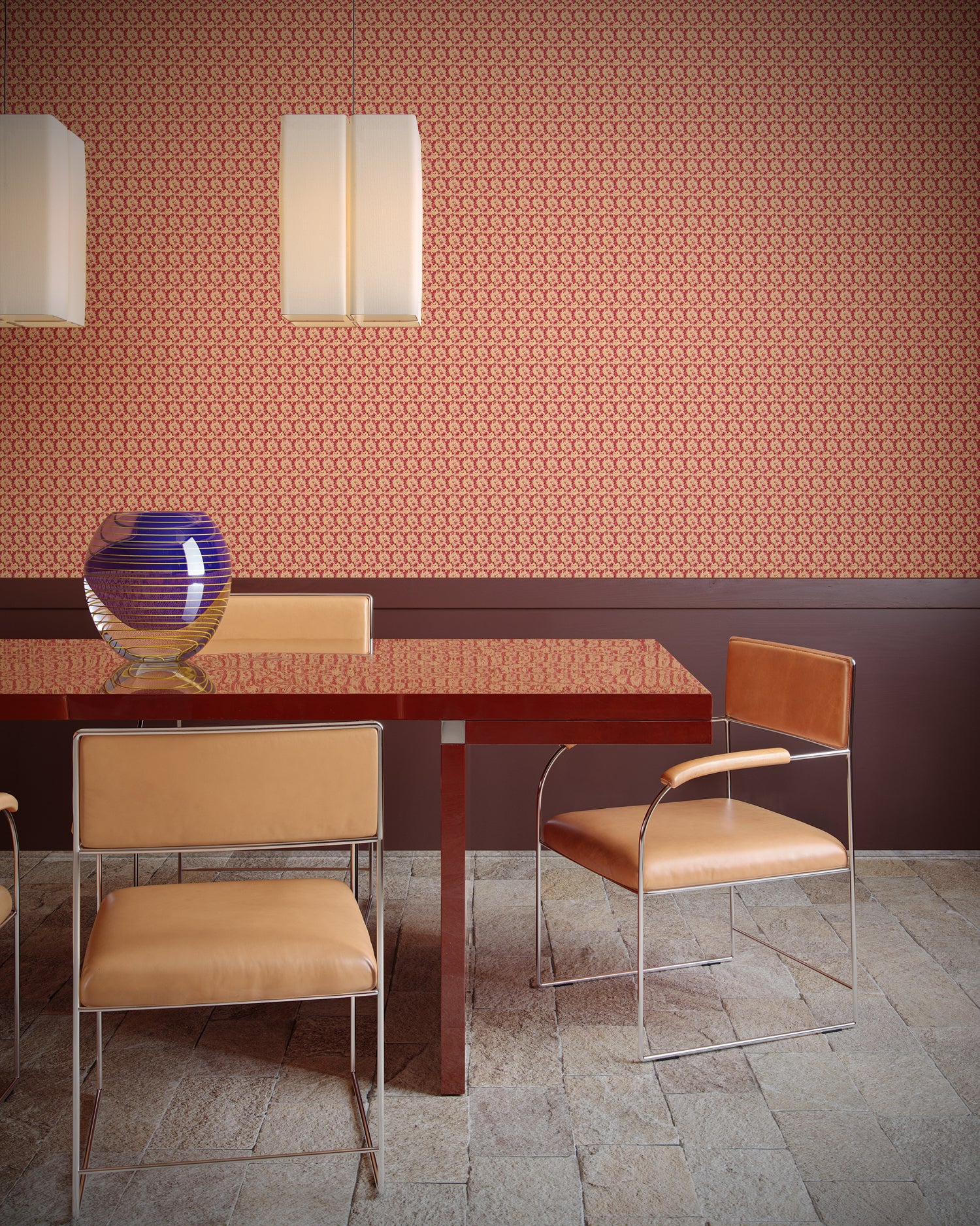 Dining area with a table and chairs against a patterned wall in orange.