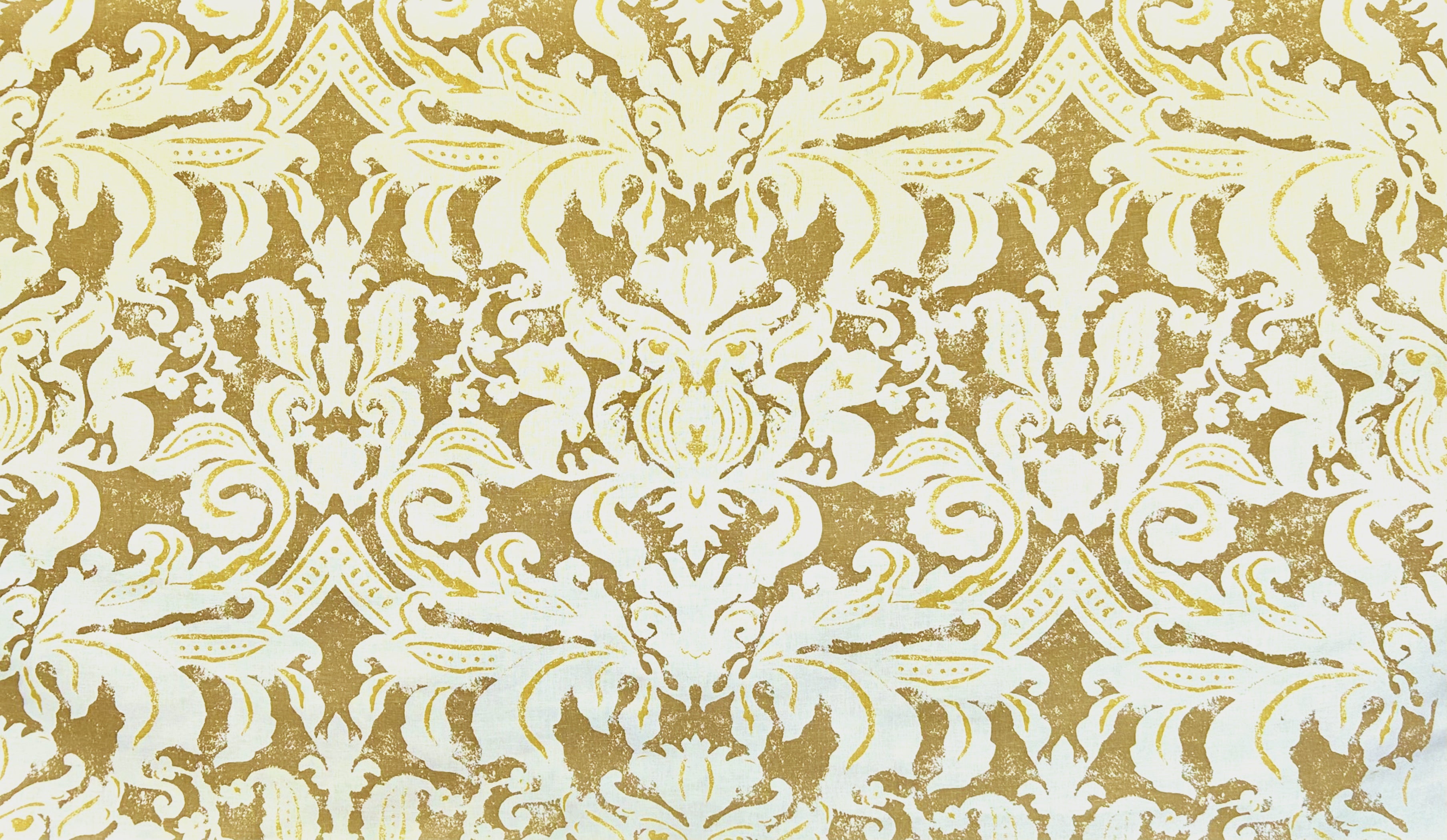 Detail of fabric in a floral damask print in white and yellow on a brown field.