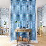 A maximalist living space with an accent wall papered in an intricate lattice print in light blue on a white field.