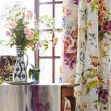 A sunny dining room tableau with a large window and curtains in a painterly floral print.