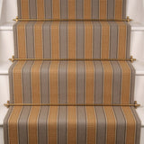 Striped flatweave runner in taupe and mustard yellow installed on white stairs.