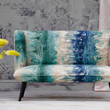 A loveseat upholstered in an abstract paint blot pattern in shades of green, navy and blue on a mottled cream field.