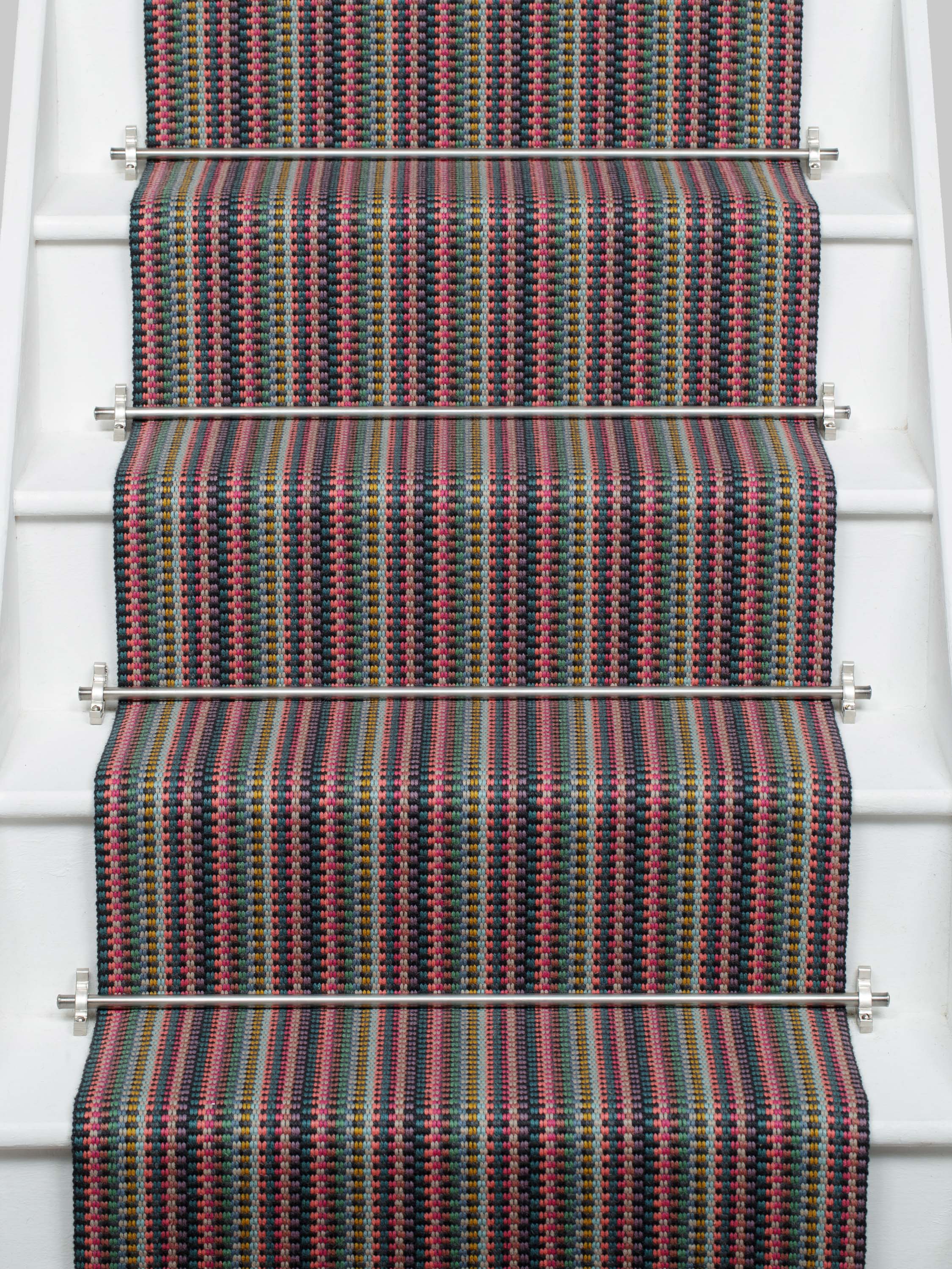 Striped flatweave runner in pink green purple blue with black border on white staircase