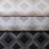 Three rolled pieces of wallpaper in different neutral colorways of a diamond lattice print.