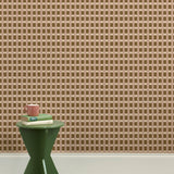 A green wooden stool with books and a mug against a wallpapered wall in a gridded check pattern in brown, cream and mauve. 