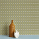 Two ceramic vases against a wallpaper in a gridded check pattern in soft shades of green.