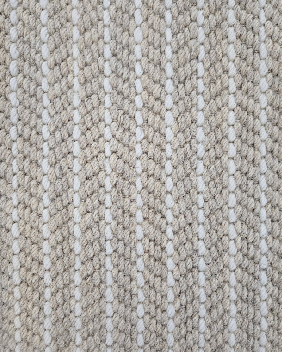 Close-up of a broadloom carpet with vertical stripes in beige and white.