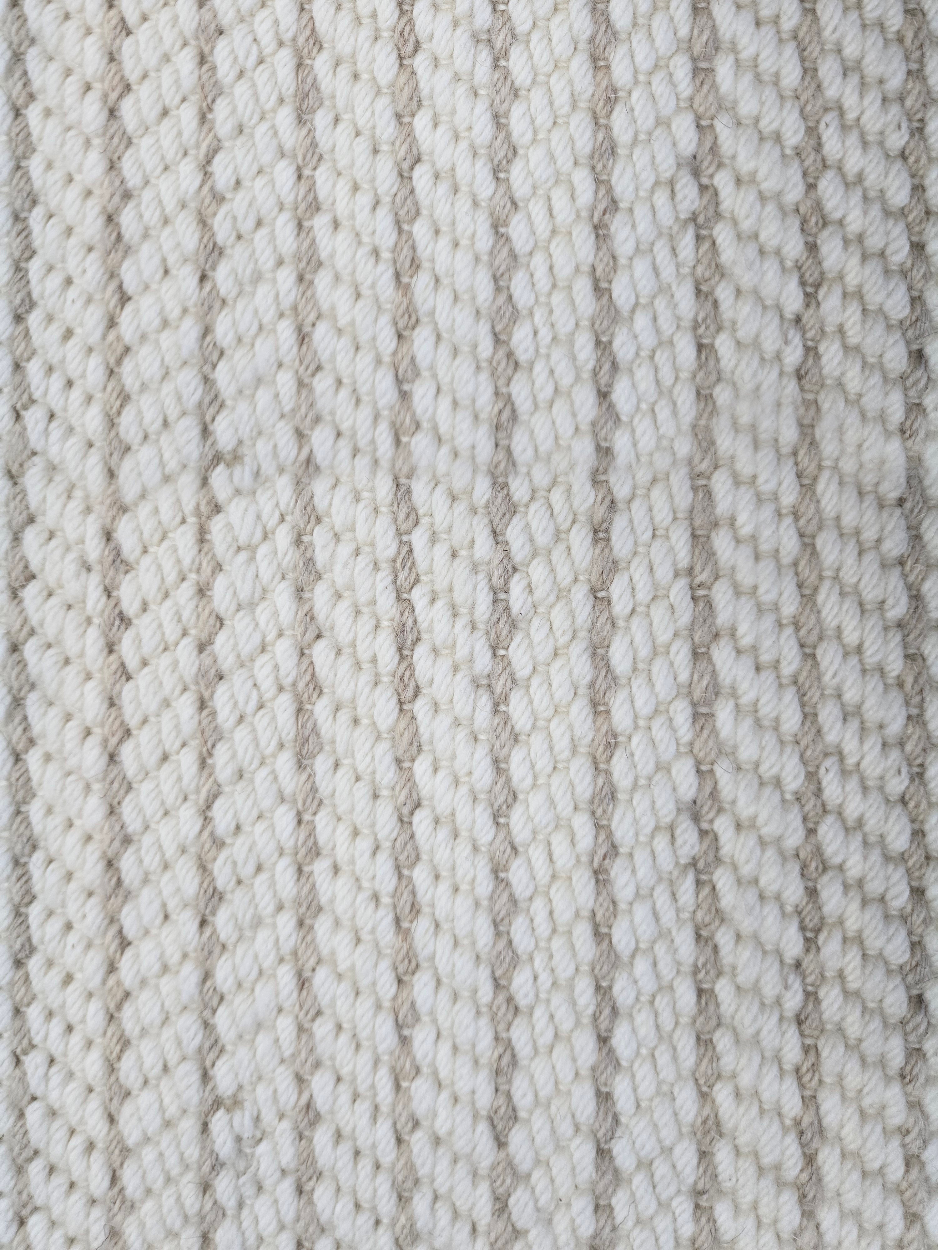 Close-up of a broadloom carpet with vertical stripes in beige and tan