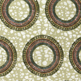 Detail of fabric in an intricate circular print in shades of green, orange and cream.