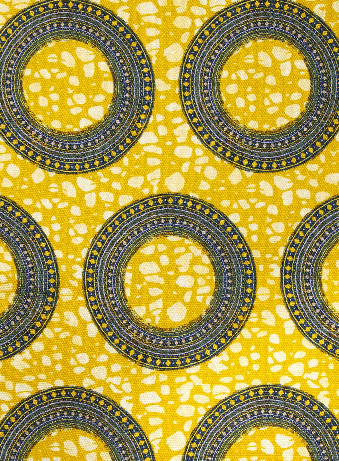 Detail of fabric in an intricate circular print in shades of yellow, blue and white.