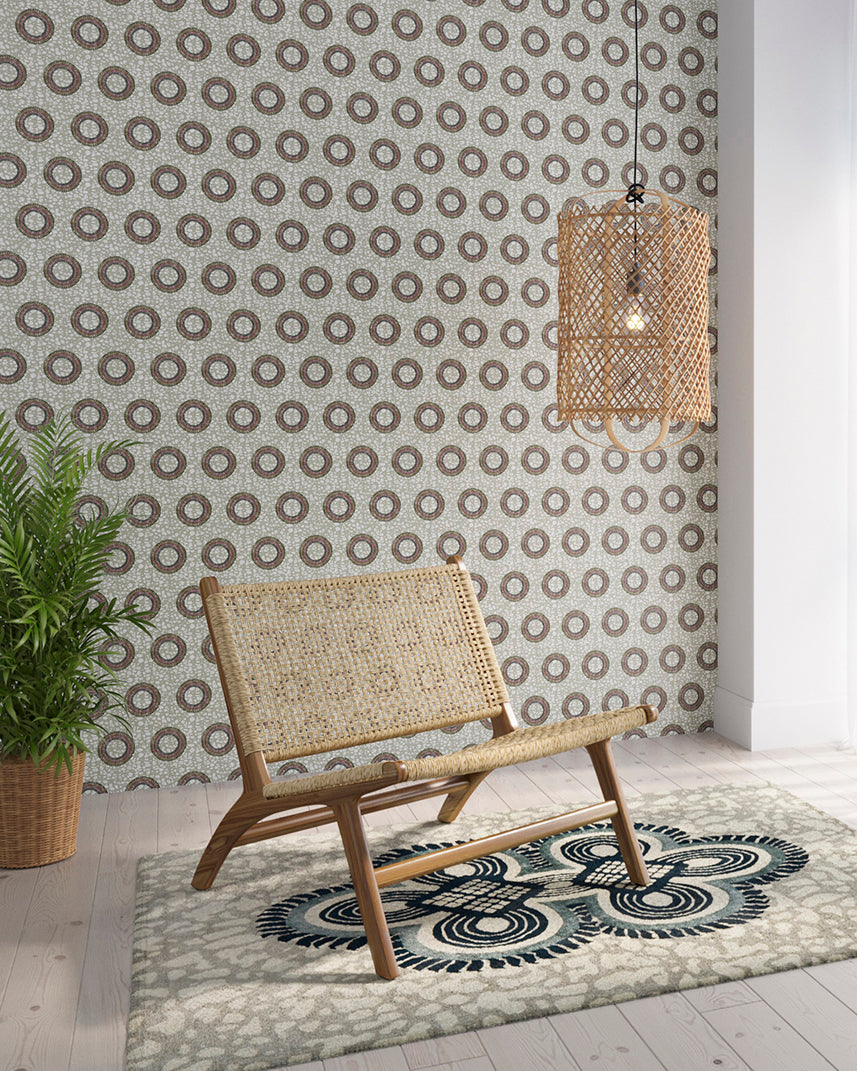 Styled living room tableau with a wall papered in an intricate circular print in shades of green, red and gray.