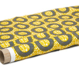 Partially unrolled fabric in an intricate circular print in shades of yellow, blue and white.