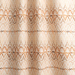 Draped fabric yardage in a painterly ikat print in shades of tan and orange on a white field.