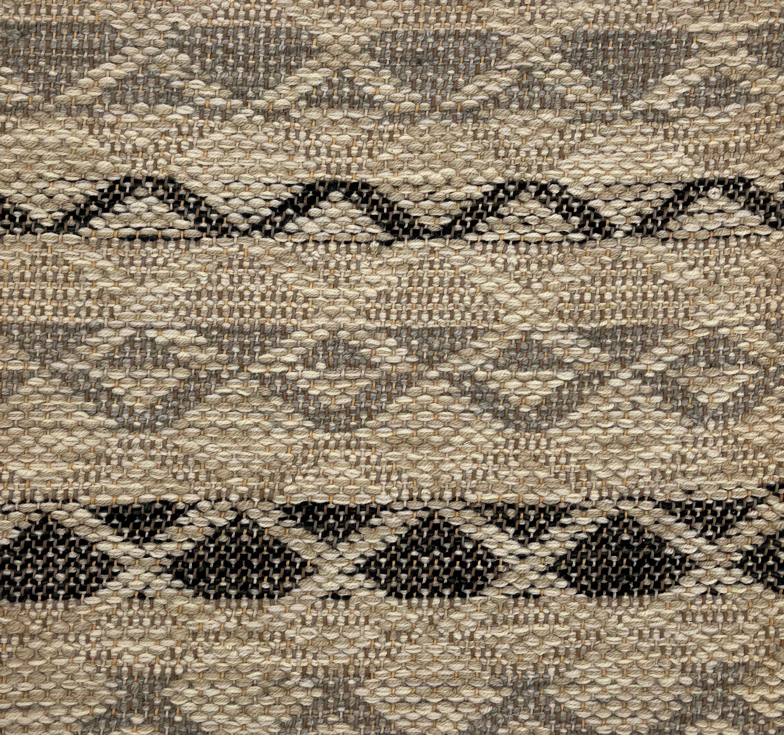 Handwoven rug detail in a lattice stripe design in black and grey