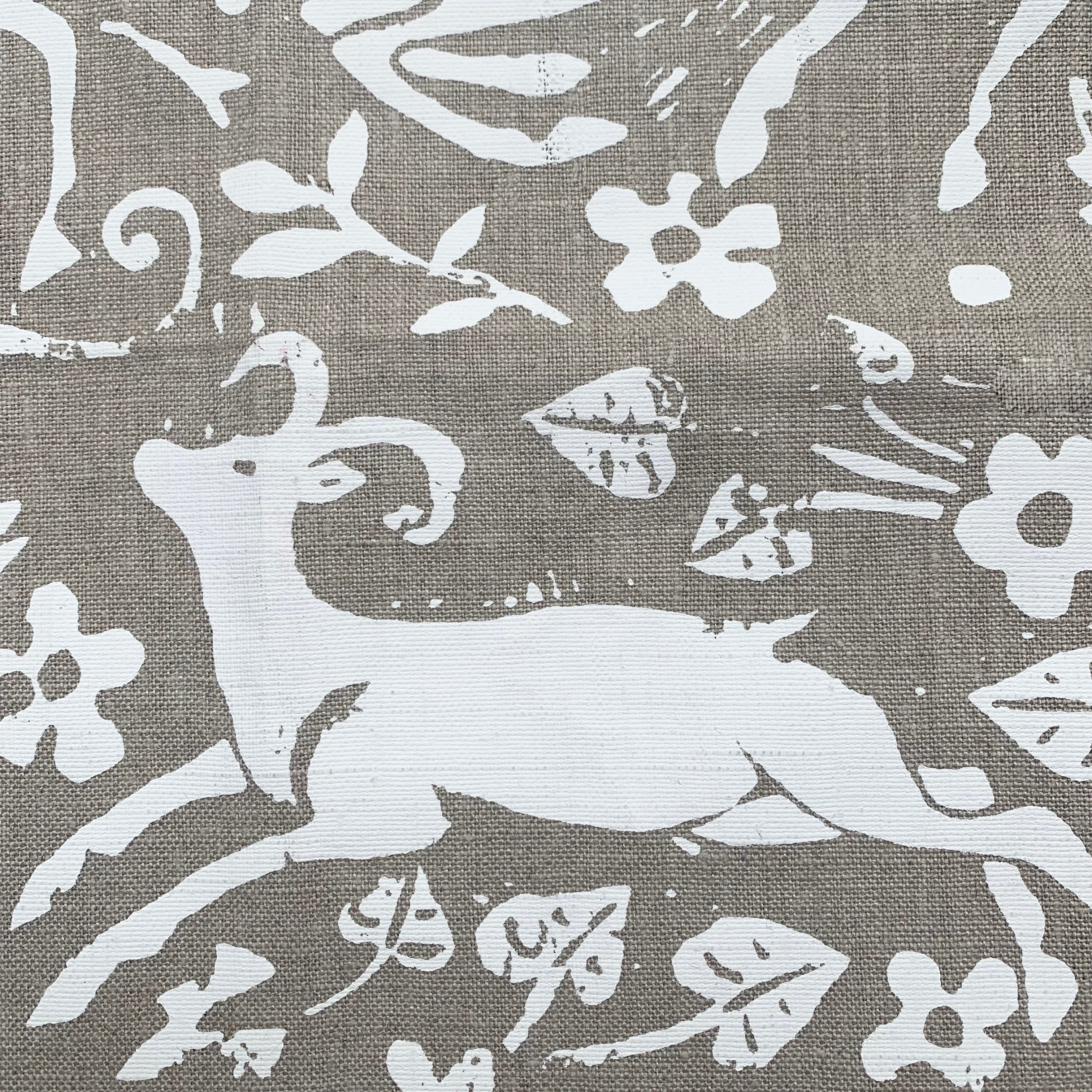 Close-up of fabric in a deer, leaf and flower print in white on a light brown field.