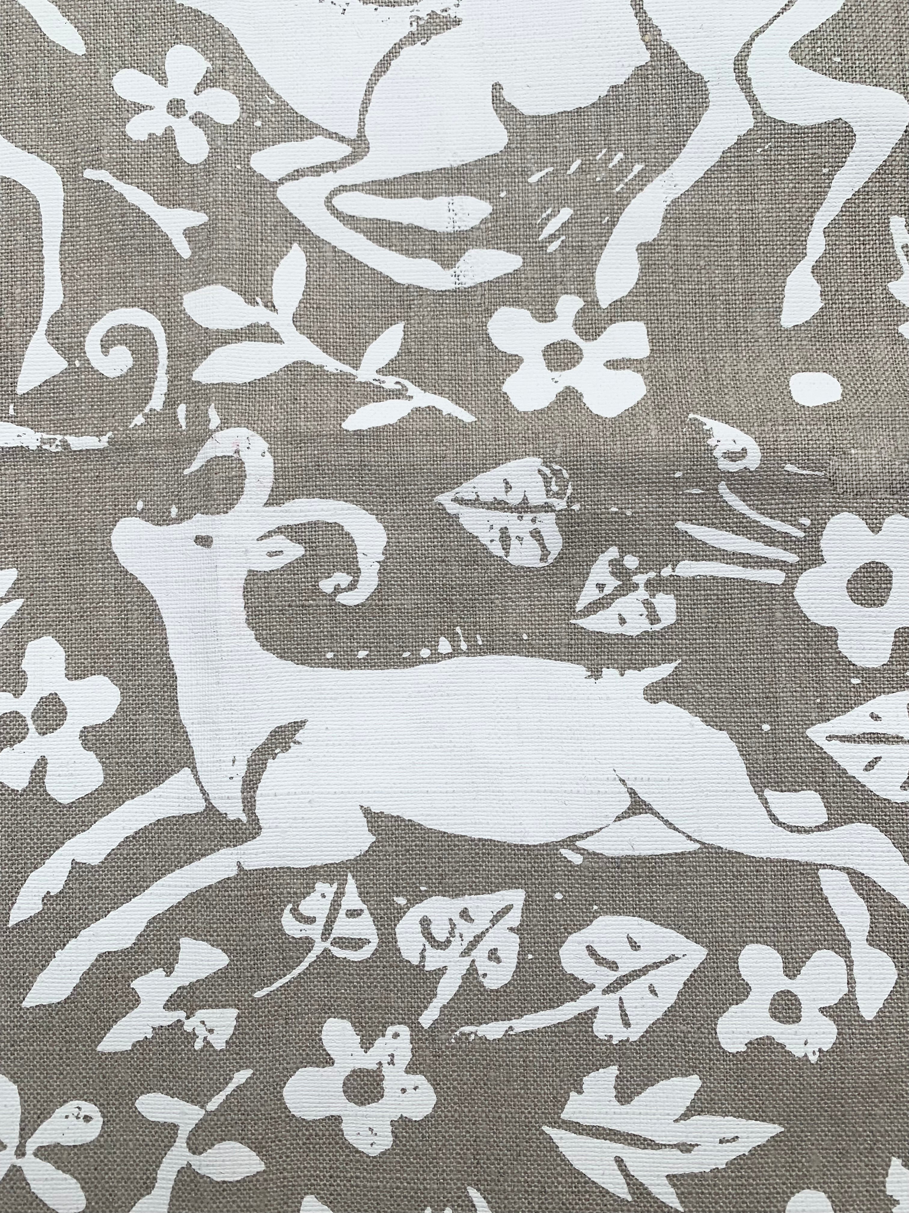 Close-up of fabric in a deer, leaf and flower print in white on a light brown field.