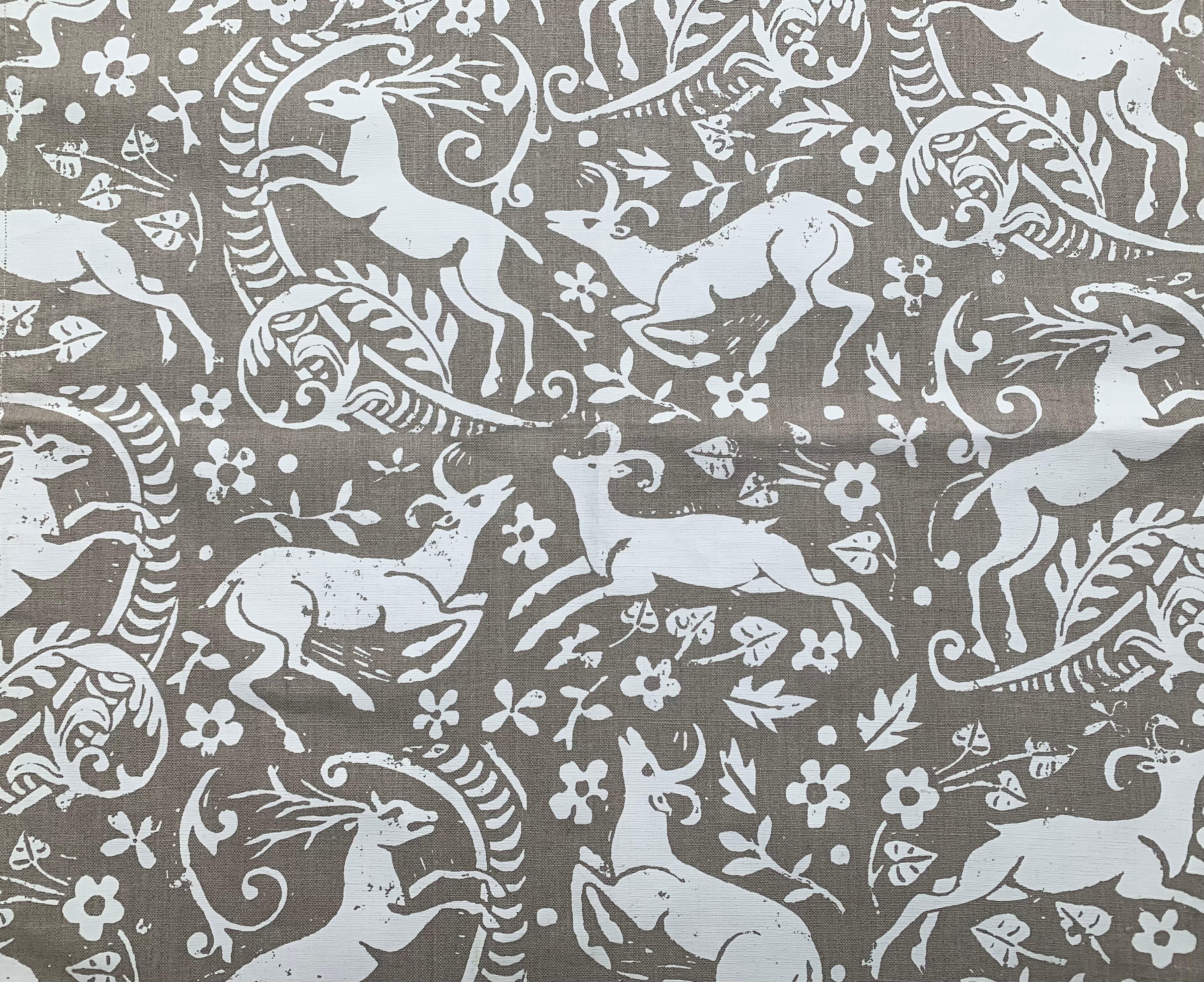 Detail of fabric in a deer, leaf and flower print in white on a light brown field.