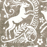 Close-up of wallpaper in a deer, leaf and flower print in white on a mottled brown field.