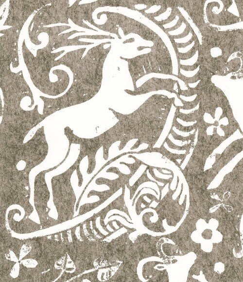 Close-up of wallpaper in a deer, leaf and flower print in white on a mottled brown field.