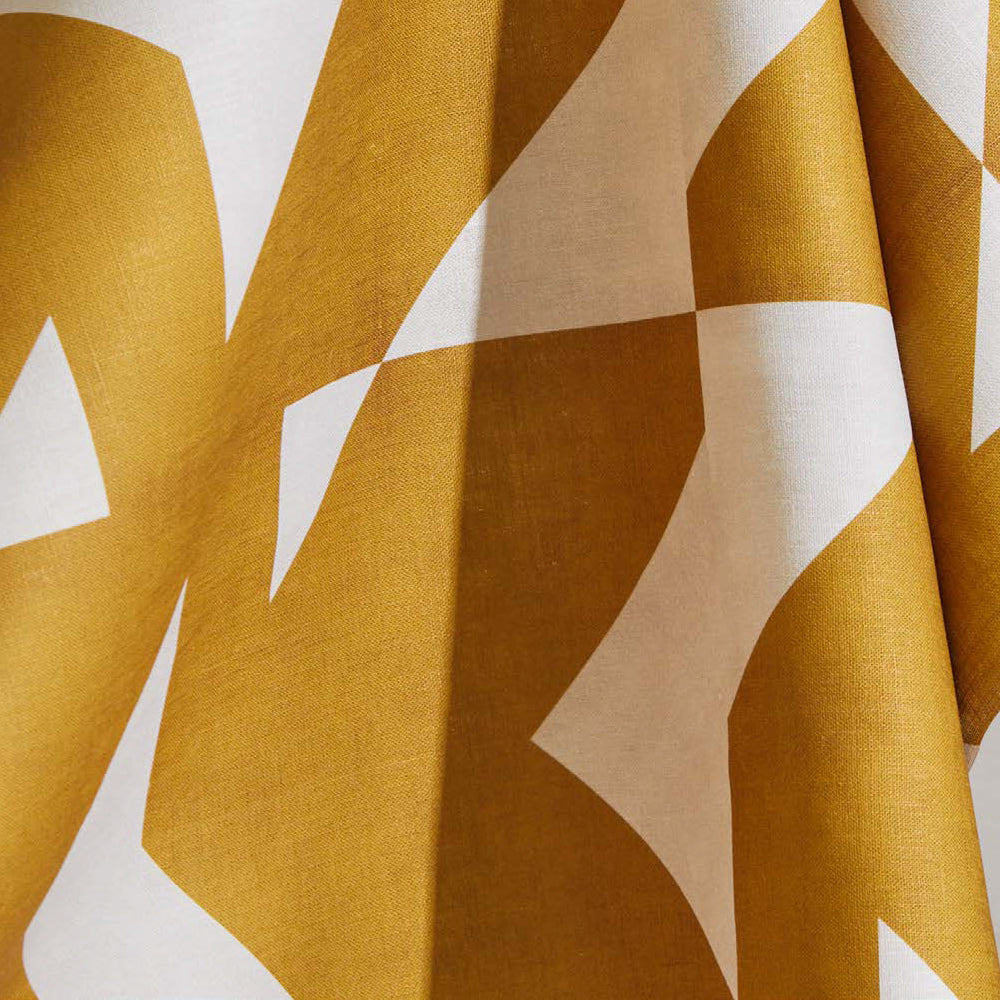 Draped fabric yardage in a large-scale geometric print in mustard on a white field.
