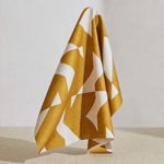 A large piece of draped fabric in a large-scale geometric print in mustard on a white field.