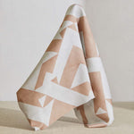 A large piece of draped fabric in a large-scale geometric print in peach on a white field.