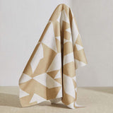 A large piece of draped fabric in a large-scale geometric print in tan on a white field.