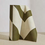 A curved partition stands on the ground, covered in a large-scale geometric print in olive on a cream field.