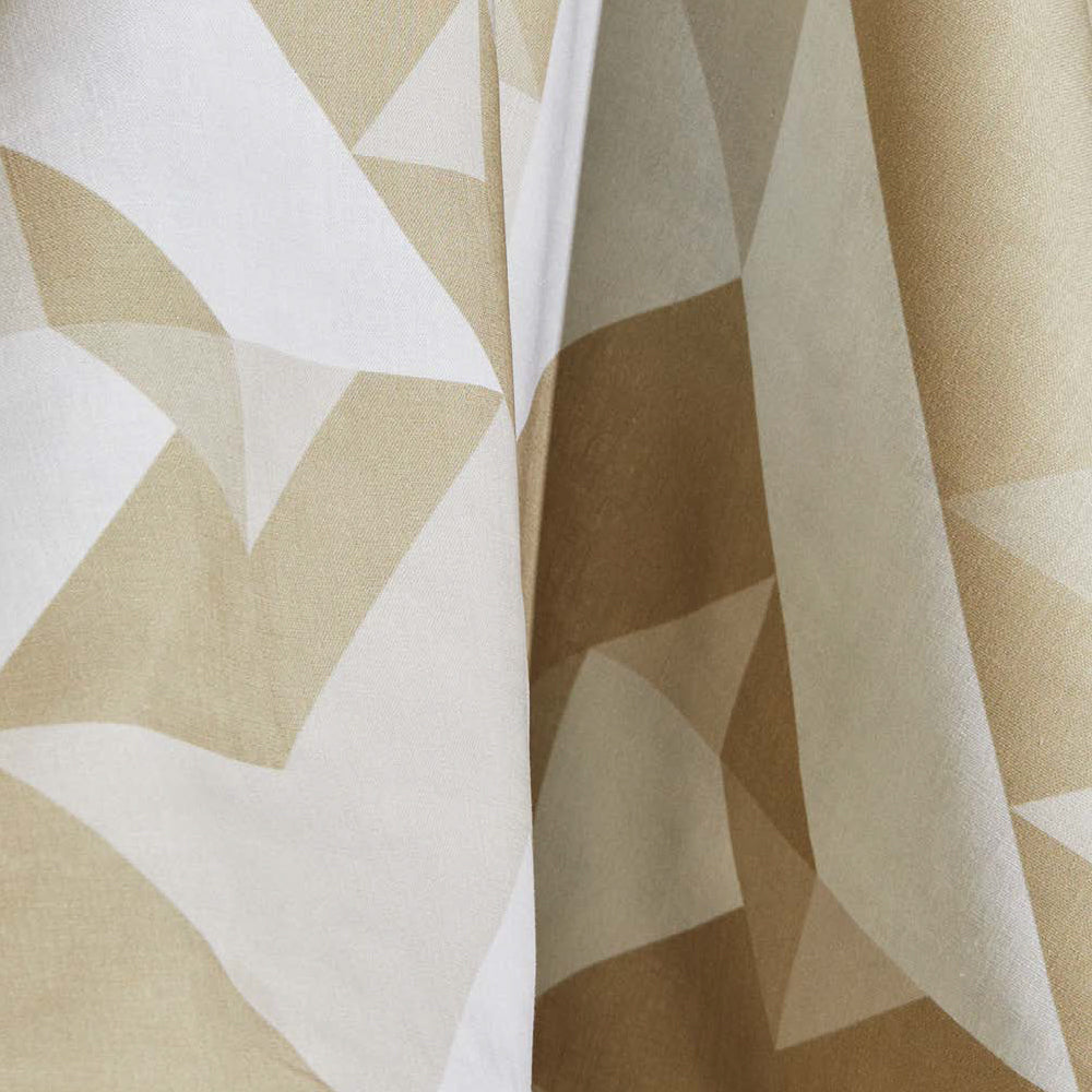 Draped fabric yardage in a large-scale geometric print in cream and tan on a white field.