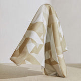 A large piece of draped fabric in a large-scale geometric print in cream and tan on a white field.