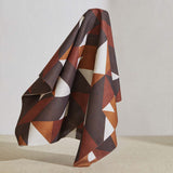 A large piece of draped fabric in a large-scale geometric print in rust and brown on a white field.