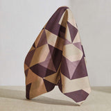 A large piece of draped fabric in a large-scale geometric print in cream, tan and purple.