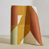 A curved partition stands on the ground, covered in a large-scale geometric print in cream, mustard and rust.