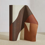 A curved partition stands on the ground, covered in a large-scale geometric print in brown, rust and cream.