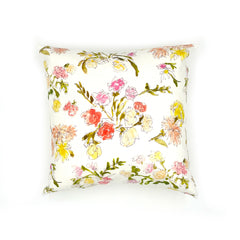 A throw pillow with a hand drawn brightly colored floral print on a white ground.