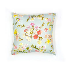 A throw pillow with a hand drawn brightly colored floral print on a light blue ground.