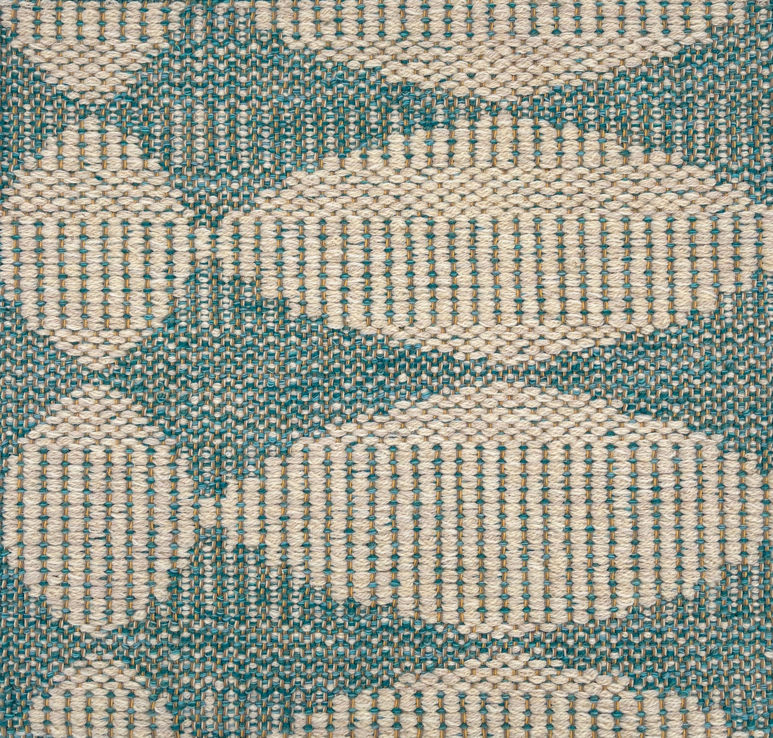 Handwoven rug detail in a circular oval design in turquoise 