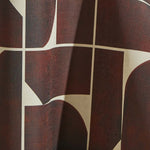 Draped wallpaper yardage in a geometric grid print in brown on a mottled cream field.