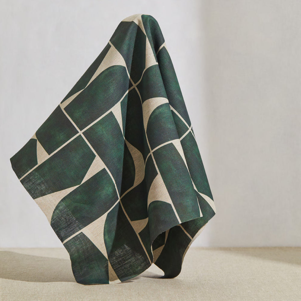 A large piece of draped fabric in a large-scale curvilinear geometric print in dark green on a cream field.