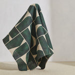 A large piece of draped fabric in a large-scale curvilinear geometric print in dark green on a cream field.